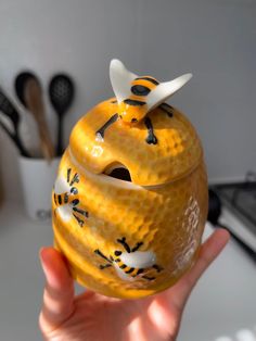 a hand holding an orange vase with bees painted on it