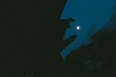 the silhouette of a person holding a cell phone at night