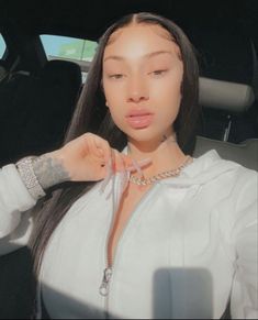 a woman with long hair wearing a white shirt and silver bracelets is sitting in the back seat of a car