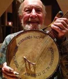 a man holding up a wooden instrument with writing on the front and side of it