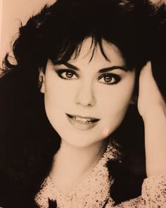 a black and white photo of a woman with her hair in the air, holding her hand up to her head