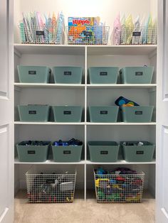 an organized closet with bins, baskets and bookshelves on the bottom shelf