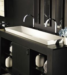 a white sink sitting under a bathroom mirror next to a black cabinet and counter top