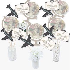 the world awaits cupcake toppers are in a vase with white flowers and an airplane