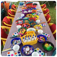 a long table covered in lots of paint and supplies