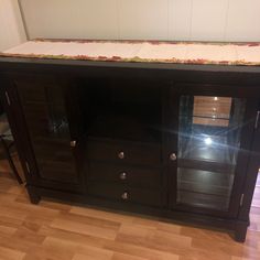 a black entertainment center with glass doors and drawers