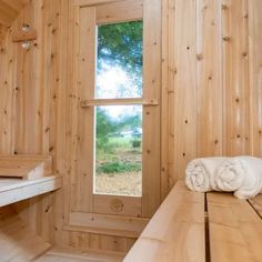 a bathroom with wooden walls and flooring next to a window that looks out onto a field