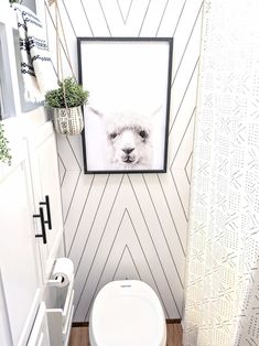 a white toilet sitting in a bathroom next to a wall with a picture on it