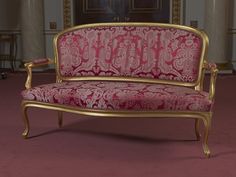 a pink and gold couch sitting on top of a red carpeted floor next to a doorway