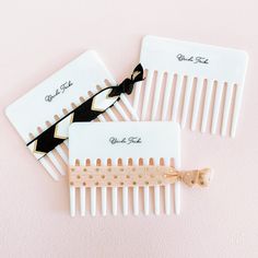 two white combs with black and gold hair clips on top of each other next to one another