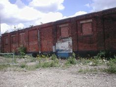 an old red brick building sitting on top of a dirt field