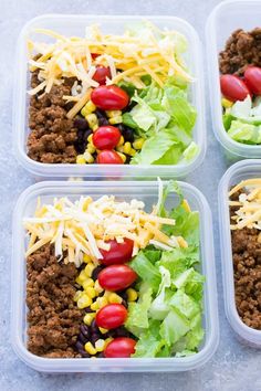 four plastic containers filled with salads and meat on top of a table next to a fork