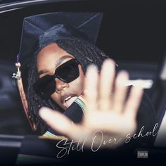 a woman wearing sunglasses and a graduation cap is sitting in a car with her hand up to the camera