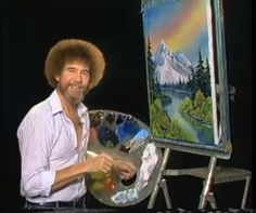 a man holding a paintbrush and an easel in front of a painting