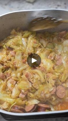 a pan filled with cabbage and sausage on top of a stove