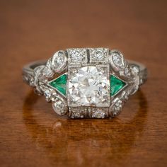 an antique diamond and emerald ring on a wooden table