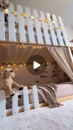 a teddy bear sitting on top of a white bunk bed with lights hanging from the ceiling