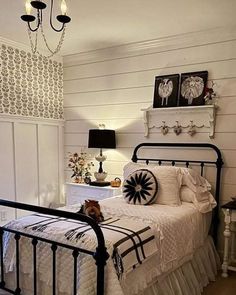 a bedroom with white walls and black iron bedspread, chandelier, nightstands and lamps