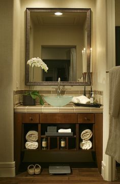 a bathroom sink sitting under a mirror next to a towel rack with candles on it