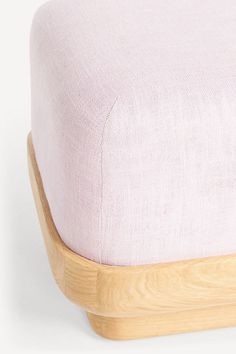 a close up of a wooden foot rest with a pink cover on top of it