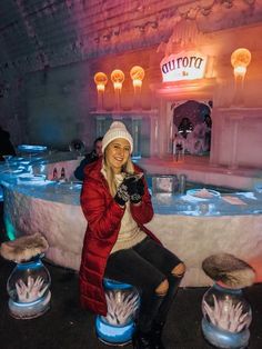 a woman sitting on top of a table covered in blue and white snow globes