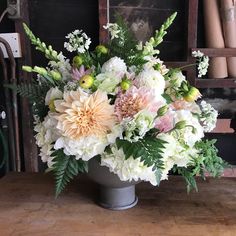 a vase filled with white and pink flowers on top of a wooden table next to a pile of wood