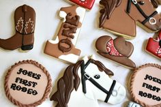 decorated cookies are arranged on a table with the words john's first rodeo written on them