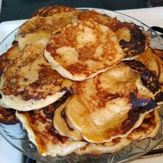 pancakes are piled on top of each other in a glass plate with syrup and butter