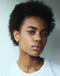 a close up of a person wearing a white t - shirt and earrings