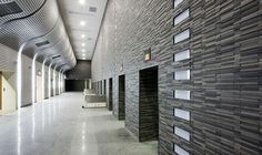 an empty hallway in a building with several doors and lights on either side of the wall