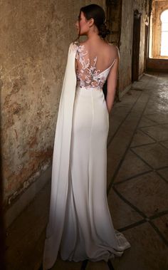 a woman in a white dress standing next to a wall