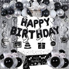 a birthday party with balloons and streamers on the wall, black and white decor