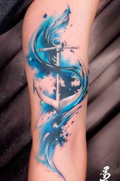 a blue and white tattoo design on the arm with watercolor paint splatters