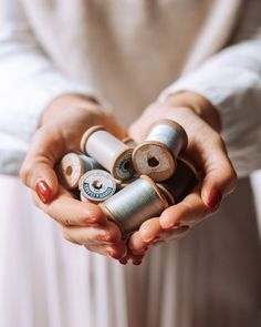 a woman holding several spools of thread in her hands