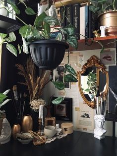 a black desk topped with lots of plants and vases next to a wall mounted mirror