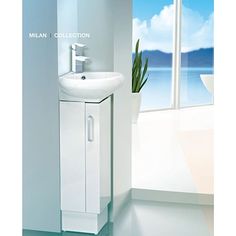 a white sink sitting next to a window in a room with a plant on it