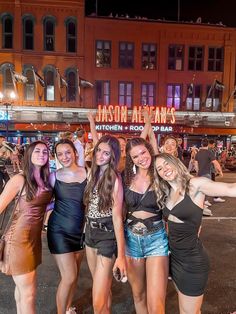 four girls are posing for the camera in front of a building