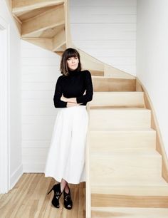 a woman standing in front of a wooden staircase