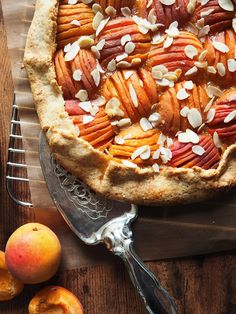 a pie with almonds and peaches on a cutting board