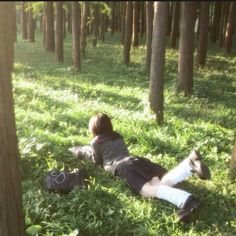 a person laying in the grass with their feet up against some trees and wearing socks