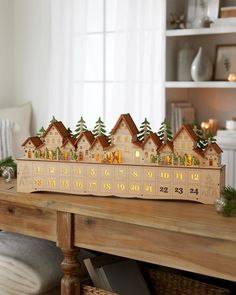 a wooden calendar with houses on it sitting on a table in front of a window