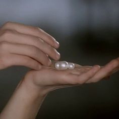 a woman holding two pearls in her hands with one being held by the other hand