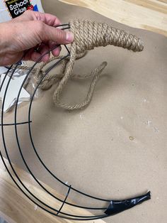 a person is holding a rope around a piece of wire on top of a table