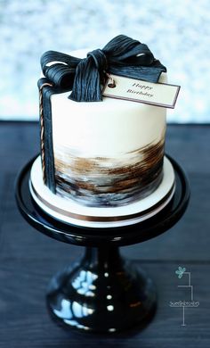 a white and black cake with a ribbon on top