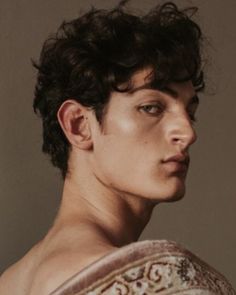 a black and white photo of a man with curly hair wearing a top over his shoulders