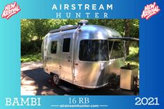 an airstream hunter trailer parked on the side of the road with trees in the background