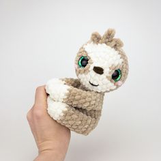 a hand holding a small stuffed animal with green eyes