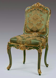 an ornately decorated green chair with gold trimming