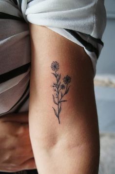 a woman's arm with a tattoo on it that has flowers growing out of it