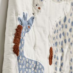 a blue and white giraffe quilt hanging on a wall next to a teddy bear